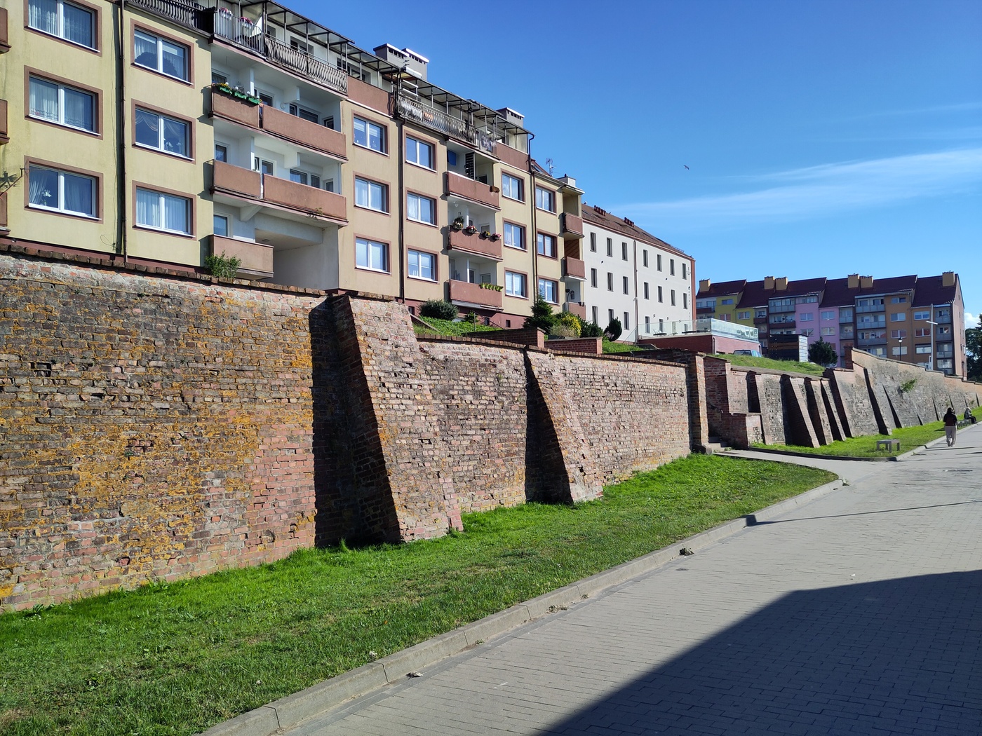Bloki na wzgórzu ponad ceglanymi, średniowiecznymi murami miejskimi.