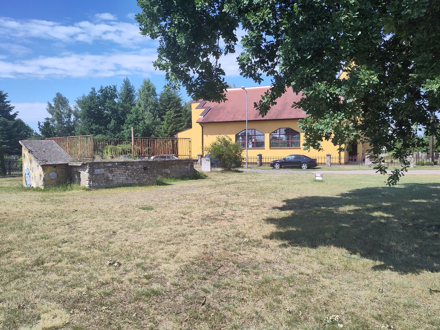 Niewielki żółty kościół z witrażem papieża. Przed nim zapewne stary schron przeciwotniczy.
